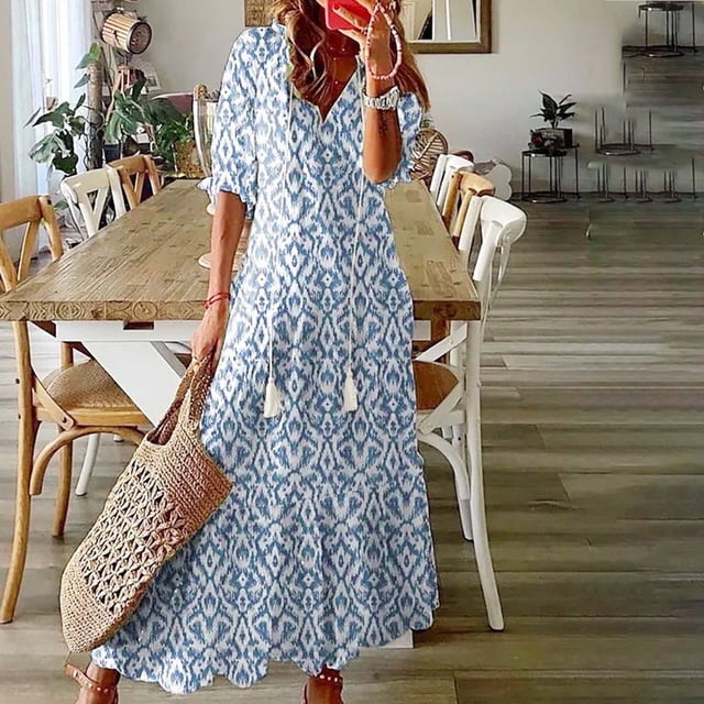 JUNWELL Robe Bohème d'Été pour Femmes, Robe Maxi Décontractée Grande Taille de Couleur Unie avec Encolure en V et accents de Franges en Dentelle. Fabriquée en Tissu polyester Léger et Respirant avec une Touche d'Élasticité, Cette Robe Est Parfaite pour les Événements d'Été comme les Sorties à la Plage, les Mariages Ou le Port Quotidien Décontracté. l'Image Représente une Femme Portant la Robe à l'Intérieur, Accessoirisée avec un Sac Fourre-Tout Tissé et des Sandales.
