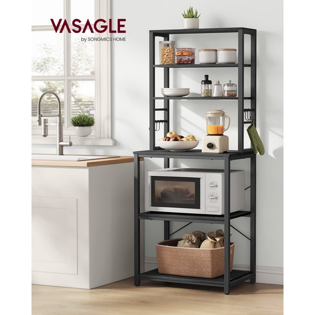 VASAGLE Coffee Bar, Baker’s Rack for Kitchen with Storage, 6-tier industrial kitchen shelving unit in charcoal gray and ink black. Features three upper shelves for jars and bowls, a middle worktop for appliances like a blender, and three lower shelves for a microwave and baskets. Includes six S-hooks for hanging utensils. Made of particleboard and steel, it measures 15.7 inches deep, 23.6 inches wide, and 65.7 inches tall. Ideal for space-saving storage in compact kitchens. Positioned in a bright kitchen setting near a sink.