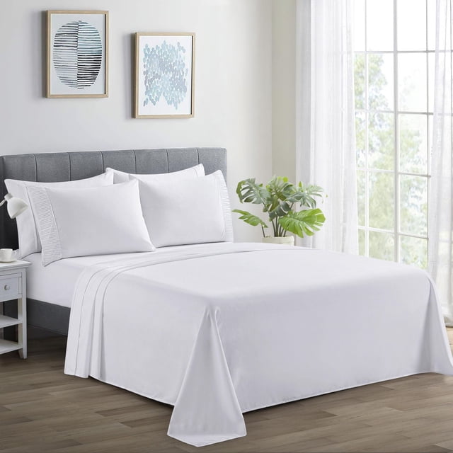Marina Decoration Ultra Soft Silky Deep Pocket Solid Rayon from Bamboo Bedding All Season Sheet Set in white on a grey upholstered bed, showing pleated pillowcases, smooth flat sheet, and deep pocket fitted sheet, in a bright bedroom with wooden floor, white nightstand, green plant, and framed abstract wall art.