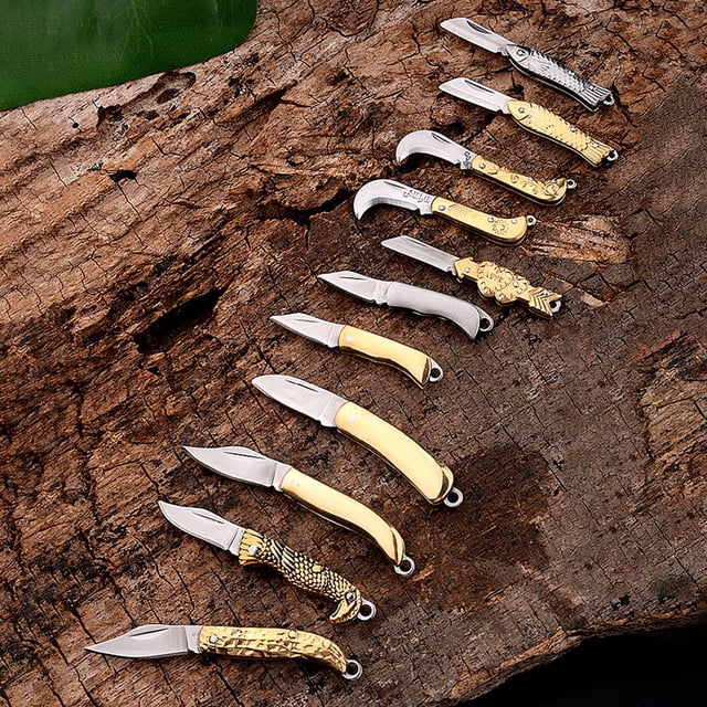 Lubelski Practical Foldable Mini Knife High Hardness Sharp Metal Pocket Knife for Home displayed in various designs and sizes on a rustic wooden surface. Constructed from durable brass and metal, these compact knives feature foldable designs and sharp blades suitable for box opening, hunting, and outdoor activities.
