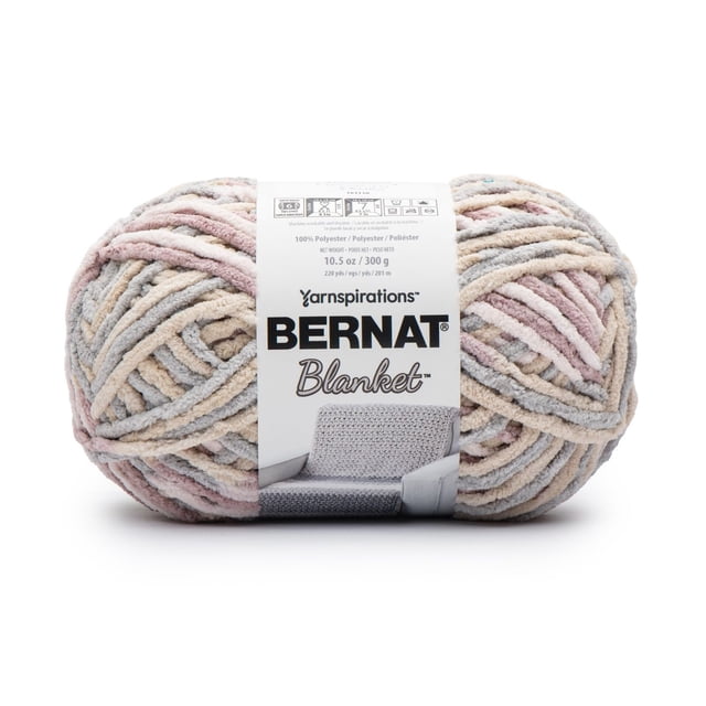 Bernat Blanket #6 Super Bulky Polyester Yarn in pastel beige, pink, and gray tones, 10.5 oz/300 g skein with 220 yards, chenille-style texture, ideal for knitting and crochet projects, wrapped with a white label showing care instructions and brand logo.