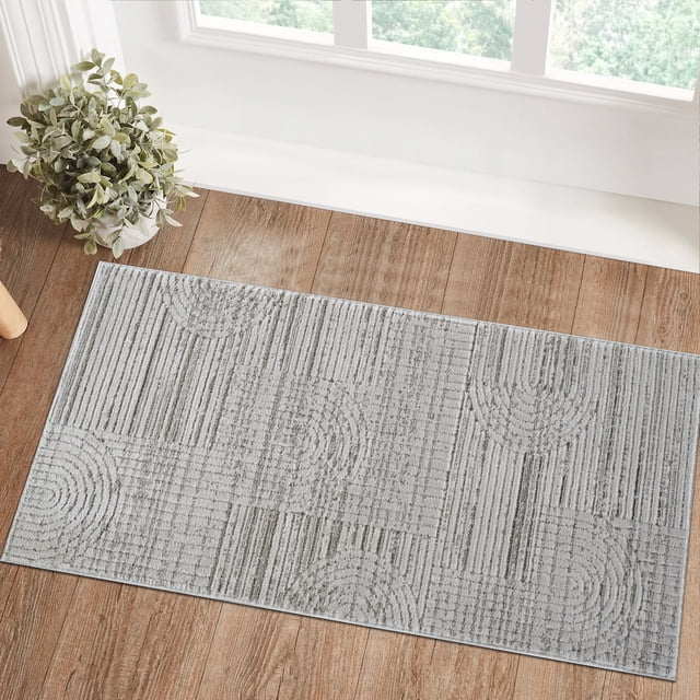 Rug Branch Astra Modern Indoor Area Rug in grey featuring a geometric pattern of linear and semi-circular shapes, placed on a wooden floor near a window with natural light and a potted plant, suitable for kitchen mats and hallways, made of easy-care polyester with jute backing.