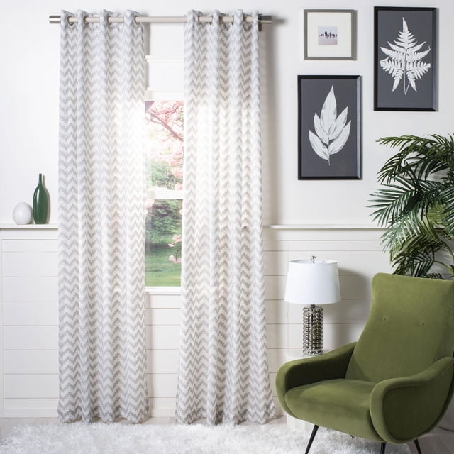 Safavieh Penda Chevron Grommet Window Panel in white and warm taupe synthetic and linen fabric with a chevron pattern, hanging on a silver metal rod with polished grommets, shown in a living room with a green armchair, white lamp, framed botanical prints, and a white shag rug, ideal for adding texture and light diffusion to windows.