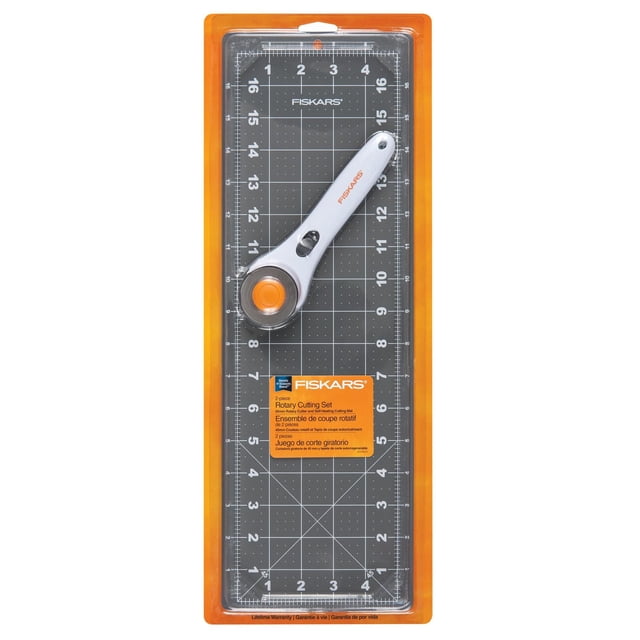 Fiskars Fabric Cutting Set (2-Piece) with a white rotary cutter featuring a 45 mm blade and orange guard, placed on a black self-healing cutting mat with white measuring grids and bias lines, all in orange packaging, suitable for accurate fabric cutting in sewing and quilting.