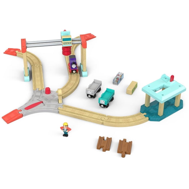 Thomas & Friends Wood Lift & Load Cargo Set For Kids Ages 2+ Years with a wooden train track featuring a 4-way crossing and easy-fit connectors, including Charlie the purple engine, two Troublesome Trucks in grey and teal, a sliding transfer crane with operator figure, two cargo pieces, and two brown track adaptors compatible with other wooden railway sets, made from sustainably sourced wood for easy assembly and creative play.
