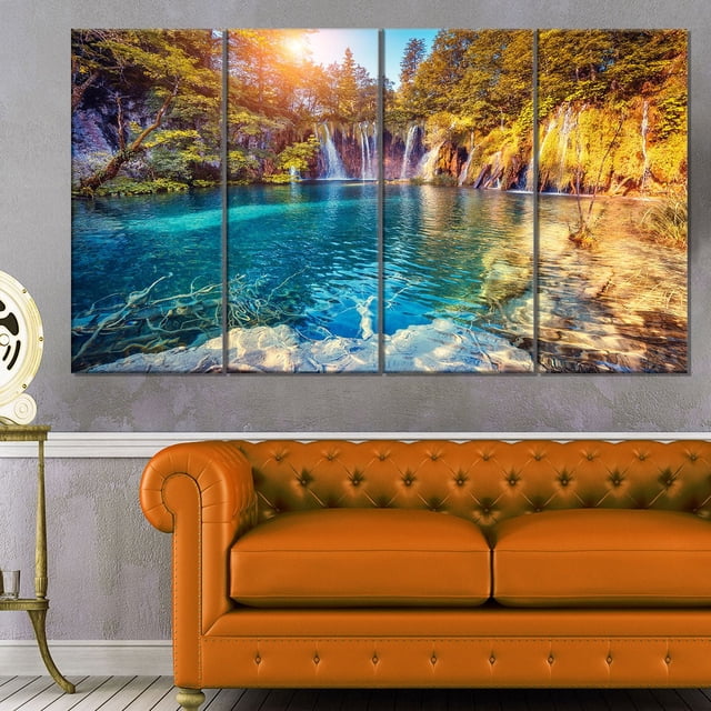 Design Art Turquoise Water And Sunny Beams Landscape Photo Canvas Art Print, a 48 by 28 inch 4-panel gallery wrapped canvas depicting a turquoise lake with waterfalls and sunlit autumn trees, printed on high-quality cotton canvas with vibrant ink, ready to hang in home décor spaces, often used to enhance natural landscape ambiance.