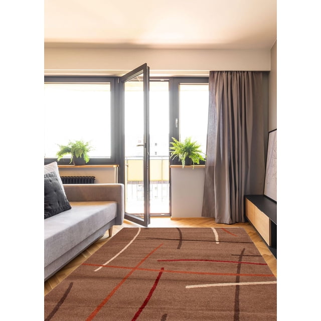 ECARPET Lotus Mod Tapis Brun 6 Pieds7 Pouces x 9 Pieds8 Pouces dans un Salon Moderne avec un sofa Gris et un Coussin Noir. le Tapis Brun Présente des Lignes Croisées Rouge, orange, Crème et Brun Foncé sur un Plancher de parquet en Bois. la Pièce Comprend des Portes en Verre à Cadre Noir, des Fougères Vertes en Pot sur des Étagères en Bois et des Rideaux Gris. Ce Tapis d'Intérieur Ajoute du Confort et du style aux Espaces d'Accent et Convient pour Définir des Zones d'Assise.