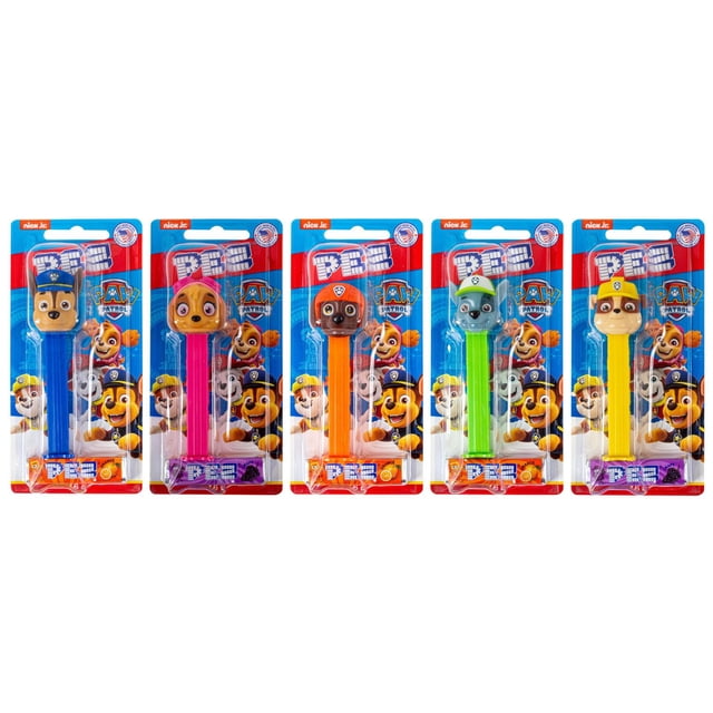 Pez Paw Patrol candy dispensers in packaging, each with a Paw Patrol character head on a colored stem in blue, pink, orange, green, and yellow. Each includes two PEZ candy refill packs in orange and grape flavors, featuring Nick Jr. and Paw Patrol branding on a blue and red card.