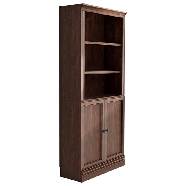 VAUXHILL & CO. Halston Standard Bookcase with Doors in dark cherry wood finish, featuring adjustable shelving and a pre-drilled back panel for a seamless look. The bookcase includes two open shelves on top and a lower cabinet with double doors for concealed storage. Designed with a 3.9-inch baseboard clearance and adjustable leveling feet for stability on uneven surfaces. Dimensions are 14.5 x 31.5 x 72.6 inches, making it suitable for home offices, living rooms, or bedrooms.