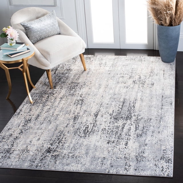 Safavieh Lagoon Hristo Damask Distressed Area Rug in soft grey and white tones with an abstract damask pattern, power loomed with synthetic yarns in a plush cut pile, placed on dark hardwood flooring under a cream upholstered chair with wooden legs and a grey textured pillow, beside a gold side table with books and flowers, and a blue vase with pampas grass near white double doors, ideal as a modern accent rug.