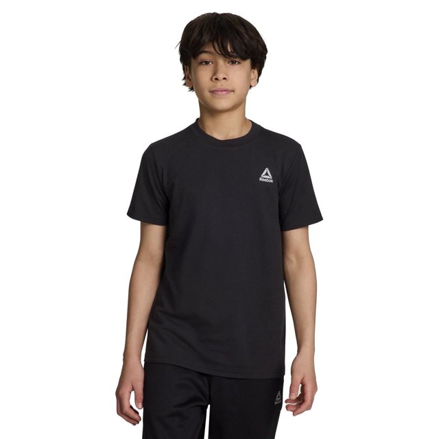 Reebok Boys Delta Core Short Sleeve Tee in black with a crew neck and short sleeves, shown front-facing on a model. Made from soft jersey fabric, it features a small white Reebok Delta logo on the left chest, offering breathable comfort ideal for active boys.