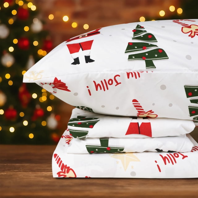 Hitime Full Size 4-Piece Christmas Sheet Set made of ultra-soft and breathable polyester with a festive Christmas pattern. The set includes a flat sheet, a fitted sheet with deep pockets for mattresses up to 16 inches, and two pillowcases. The design features holiday-themed prints such as Christmas trees, Santa Claus, and candy canes on a white background. Suitable for all seasons, the sheets are wrinkle and fade-resistant, ensuring durability and easy maintenance. Shown in a warm holiday setting with a decorated Christmas tree in the background.