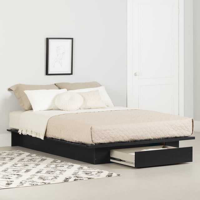 South Shore Primo Full/Queen Platform Bed with Drawer in Black Oak, featuring a minimalist low-profile frame with a spacious under-bed drawer on full-extension ball-bearing metal slides for extra storage. The bed is dressed in beige bedding with neutral pillows, set against a light grey wall with simple line art and a patterned rug on the floor, suitable for modern bedroom decor.
