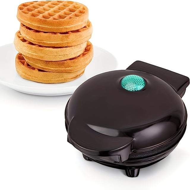 1pc Mini Waffle Maker Machine with a nonstick surface, designed for making pancakes, waffles, and breakfast items. The compact black waffle iron features a green indicator light on the lid and operates with a US plug at 110V-130V. Rated below 1000W, it has a pan diameter under 25cm and is not detachable for washing. A stack of golden waffles is displayed on a white plate beside the machine.