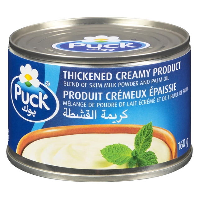 Puck Boîte de Produit Crémeux Épaissie 160 g avec Étiquette Bleue Affichant le logo Puck et le Texte en Anglais, Français et Arabe Décrivant un Mélange de Poudre de Lait Écrémé et d'Huile de Palme. la Boîte Présente un Produit Laitier Crémeux Convenant à la Cuisine, aux Trempettes et aux desserts, Montré avec une Garniture de Feuilles de Menthe Fraîches.