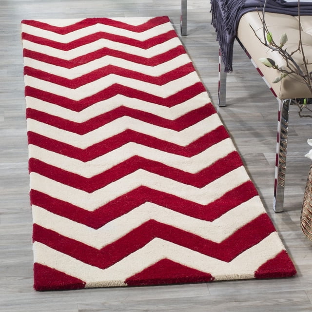 Safavieh Chatham Jake Tapis à Rayures Zigzag avec construction en Laine Tuftée à la Main, Hauteur de Poil Moyenne et Rayures Zigzag Rouges et Crème Audacieuses, Montré sur un Plancher de Bois Clair à Côté d'Un Banc beige avec Pattes Chromées et un Jeté Foncé, Idéal pour Ajouter une Touche Contemporaine aux Intérieurs de la Maison.