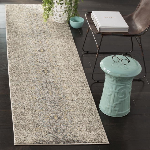 Safavieh Monaco Elsdon Abstract Area Rug runner with muted beige and gray abstract pattern on dark hardwood floor, beside a brown leather chair, white ceramic planter with greenery, turquoise bowl, and ceramic stool with eyeglasses, suitable as an accent rug for hallways or entryways.