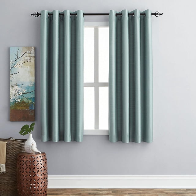 Hometrends Faux Silk Grommet Room Darkening Window Panel in teal with thermal lining, hanging on a black curtain rod with grommet top, covering a white window frame in a room with light gray walls, wooden floor, and a copper side table with a white bird figurine and green leaf in a vase, ideal for reducing light, drafts, and noise.