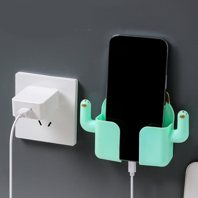 Tv Wall Mount 50 Inmobile Phone Storage Rack Storage Box Wall Mounted Tv Aircondition Remote Control Bedside Phone Charging Storage Bracket Bathroom Kitchen Storage Rack. A light green wall-mounted phone holder securely holds a smartphone while charging, attached to a wall near a power outlet. The compact plastic design features two side arms for stability and is suitable for organizing devices in various spaces like bedrooms, bathrooms, or kitchens.