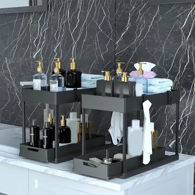 Under Sink Organizers and Storage, a 2-tier pull-out organizer with sliding drawers, crafted from ABS plastic and wrought iron pillars for durability. Shown on a marble countertop, it holds bathroom essentials such as soap dispensers, towels, and bottles. Includes hooks and cups for hanging small items, ideal for kitchen or bathroom storage solutions.