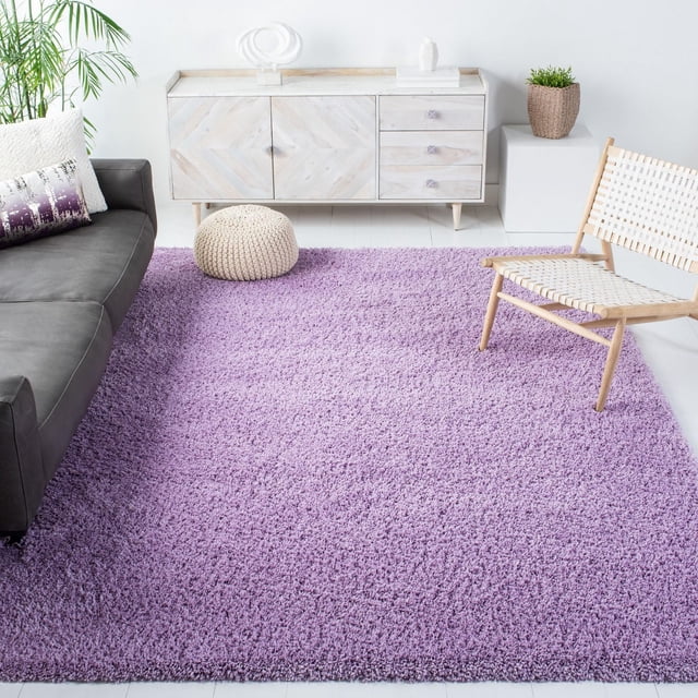 Safavieh California Tapis Shag en Peluche Uni Couleur Lavande avec une pile de Polypropylène dense de 4,5 Kg/m2, Exposé dans un Salon Lumineux avec un sofa Gris, une Chaise en Bois Tressé, un pouf Tricoté et un Buffet en Bois Clair, Idéal pour Ajouter Douceur et Chaleur à la Déco de la Maison.
