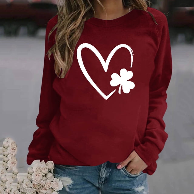 Fashion Womens Print Round-Neck Pullover Tops Long Sleeve Comfortable Blouse Sweatshirt in a deep red color with a white heart and clover print on the front. The sweatshirt features a casual, relaxed fit with long sleeves and a round neckline. Made from polyester, it is suitable for daily wear and home use across all seasons. The model pairs it with distressed denim jeans, holding a bouquet of white roses in a casual outdoor setting.