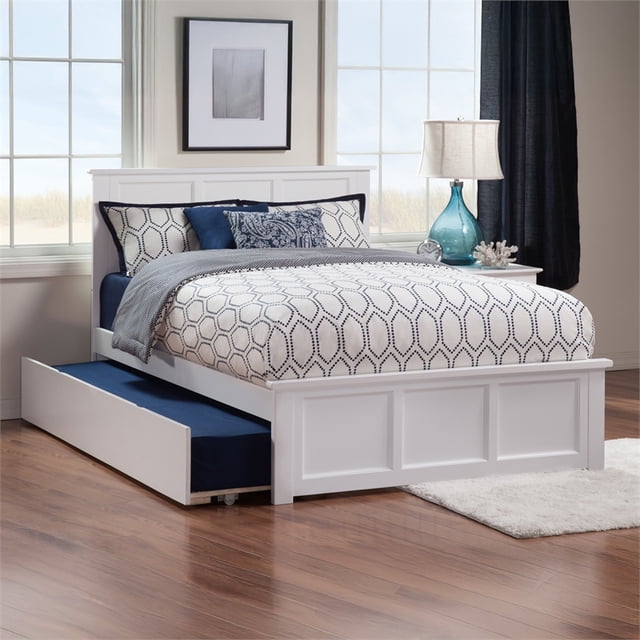 Madison Lit Plateforme Complet avec Pied de Lit Assorti et Lit Gigogne Simple en Blanc. Ce Lit Gigogne Présente une Tête de Lit à Panneaux Classique et une construction en Bois Franc Massif, avec un Lit Gigogne Simple Qui Se Déroule Facilement des Deux Côtés pour un Espace de Sommeil Supplémentaire. le Système de Lattes Robuste Supporte les Matelas Sans Sommier. Idéal pour les Installations de Meubles de Chambre, Montré dans une Pièce Lumineuse avec Plancher de Bois et accents Décoratifs.