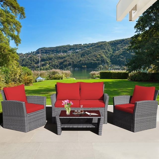 Gymax 4PCS Patio Rattan Conversation Set with two armchairs, one loveseat, and a coffee table featuring a tempered glass top. The mix grey rattan and red cushions create a stylish outdoor furniture set, perfect for patio seating or leisure in outdoor spaces.