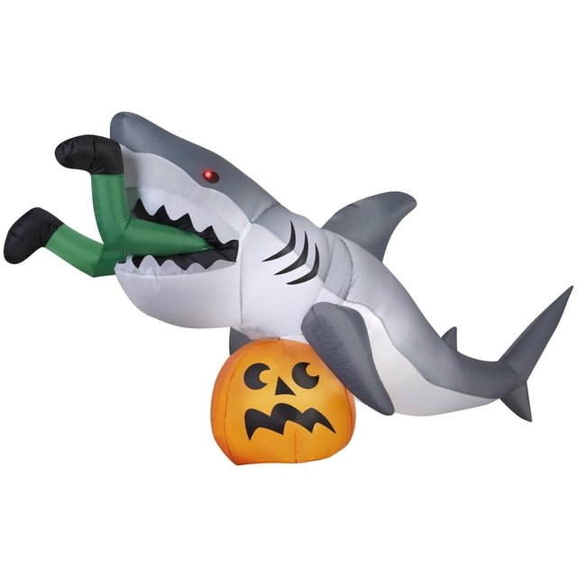 Scène de Collation de Requin Gonflable d'Halloween Animée Airblown Gonflable Mettant en Vedette un Requin Gris et Blanc avec un Oeil DEL Rouge Qui Tourne d'Un Côté à l'Autre, Mordant des Jambes Vertes Qui Sortent de Sa Bouche au-Dessus d'Un jack-o'-lantern orange avec un Visage Effrayé, Conçue pour une Décoration d'Halloween Extérieure Facile avec Auto-Gonflage et Éclairage DEL.