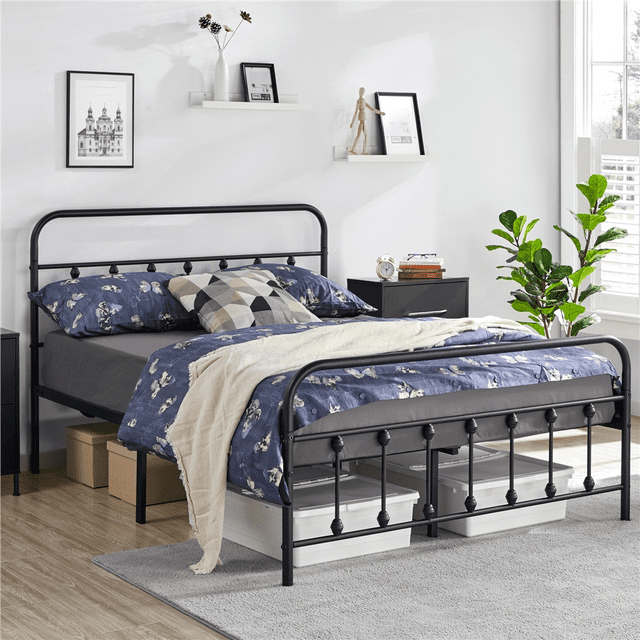 Yaheetech Lit Plateforme Classique en Métal Fer avec Tête de Lit et Pied de Lit Hauts en Noir, Format Double. le Lit Présente un Cadre en Métal Enduit de Poudre avec des accents Boule vintage et des Courbes Élégantes, Créant une Ambiance Industrielle vintage. Il Comprend une Tête de Lit Haute pour une Assise Confortable et un Espace de Rangement de 12,6 Pouces sous le Lit. le Lit Est Présenté dans un Cadre de Chambre Moderne avec une Literie Florale Bleue, un Jeté beige et des Boîtes de Rangement en Dessous.
