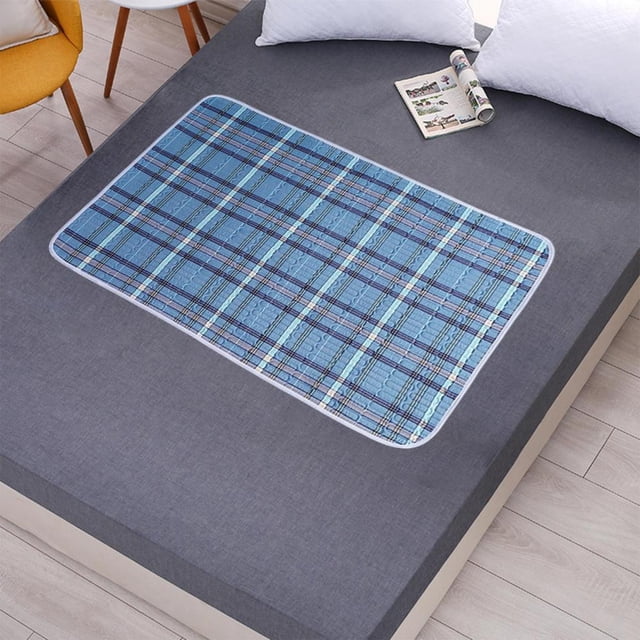 Feltree Extra-Large Washable Underpad, 60x40 Inch waterproof bed pad with non-slip back, displayed on a grey mattress. The pad features a multicolor plaid design and is crafted from breathable cotton with a TPU waterproof membrane for reusable incontinence, postpartum, and menstrual care. Suitable for beds, wheelchairs, and other surfaces.
