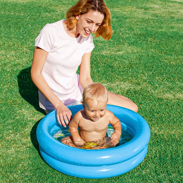 Piscine Gonflable Ronde en PVC Épaissie et Gonflable pour Enfants, Bébés et Tout-Petits, Illustrée d'Une Couleur Bleue Vibrante. la Piscine Présente un Fond Antidérapant et un Coussin Central Intérieur pour Plus de Sécurité et de Confort. un Bébé Est Assis à l'Intérieur de la Piscine, Surveillé par un Adulte, dans un Cadre Extérieur Gazoné. la Piscine Mesure Environ 60cm x 60cm x 16cm (23.62 Pouces x 23.62 Pouces x 6.3 Pouces) et Est Fabriquée en PVC Épaissi et Écologique avec une Technologie hot-melt Sans Joint pour
