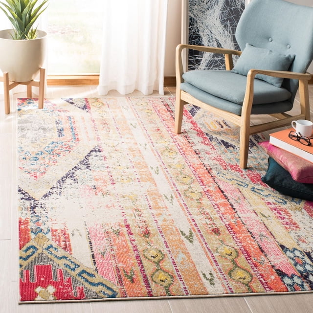 Safavieh Madison Christabella Overdyed Striped Area Rug featuring a multicolored distressed stripe pattern in red, orange, yellow, blue, and beige tones, power loomed for durability. Displayed in a bright room with light wood flooring, styled with a light blue wooden armchair, stacked cushions, books, a coffee cup, and a potted plant by a sheer curtain, ideal for vibrant transitional home decor.
