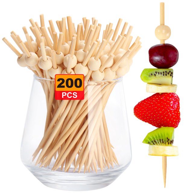 200PCS Cocktail Picks, Natural Fancy Toothpicks for Appetizers, crafted from sturdy bamboo with a wooden ball handle. The image features a glass container filled with 200 natural-colored bamboo picks, each topped with a smooth wooden ball for easy grip. A separate skewer displays fruit pieces like strawberry, kiwi, banana, and grape, demonstrating their use for appetizers, desserts, and beverages. Perfect for parties, weddings, and catering events.