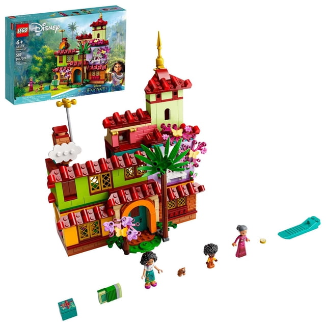 LEGO Disney The Madrigal House 43202 Toy Building Kit featuring a three-level house with red tiled roofs, green and yellow walls, a tower with a golden spire, and floral decorations including a palm tree. The set includes mini-doll figures of Mirabel, Abuela, and Antonio, plus capybara and butterfly figures, a book, a gift box, and a blue slide accessory. The box with Disney and LEGO branding is shown in the background.