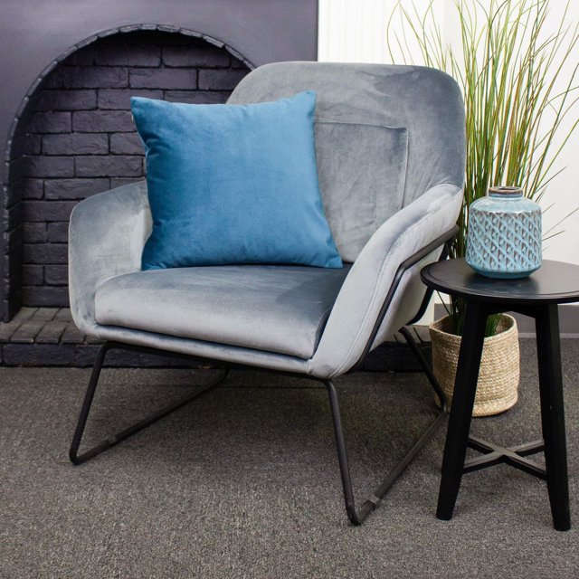 Franklin Luxury Cushion Cover (no insert included) in blue displayed on a grey velvet armchair with black metal legs, beside a black side table with a blue ceramic vase and woven basket with tall green grass, featuring soft polyester fabric ideal for decorative throw pillow use.