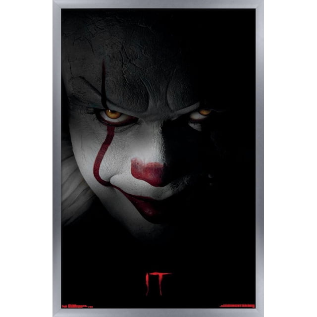 IT - Pennywise Wall Poster, 22.375" x 34" framed poster with a black background and red 'IT' text near the bottom, featuring a satin finish and lightweight frame by Trends International, ideal for home décor in bedrooms, offices, or dorm rooms.