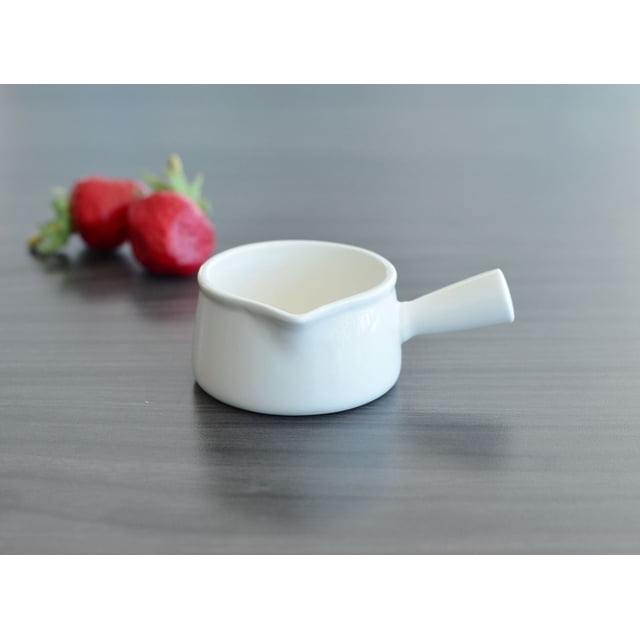 Essentials Mini Coupelle à Sauce de 1,3 Oz en Porcelaine Blanche durable avec Petit Bec et Poignée, Montrée sur une surface en Bois Foncé avec Deux Fraises Floues derrière, Convient pour Servir des sauces, des Garnitures Ou des hors-D'œuvre Format Bouchées.