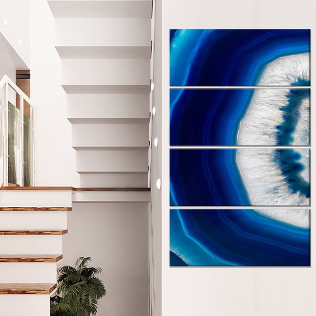 Design Art Blue Agate Crystal Abstract Digital Art Canvas Print gallery-wrapped on a 1-inch wood subframe, divided into four horizontal panels displaying a blue and white agate crystal pattern, ready to hang on a white wall beside a modern staircase with wooden steps and a green potted plant, suitable for enhancing home décor.