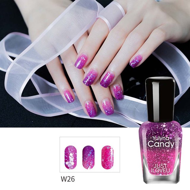 EARKITY Nail Polish, Quick Drying Long-Lasting Nail Varnish, featuring a temperature control color-changing effect. The image shows manicured nails transitioning from pink to purple with glitter accents, demonstrating the polish's ability to change color based on temperature. The bottle of nail polish is displayed in the foreground, labeled 'Yulyna Candy Just I Love U,' with a vibrant pink shade and glitter particles. Suitable for natural, gel, acrylic, and fake nails, this polish offers quick drying and long-lasting results without the need for a UV lamp.