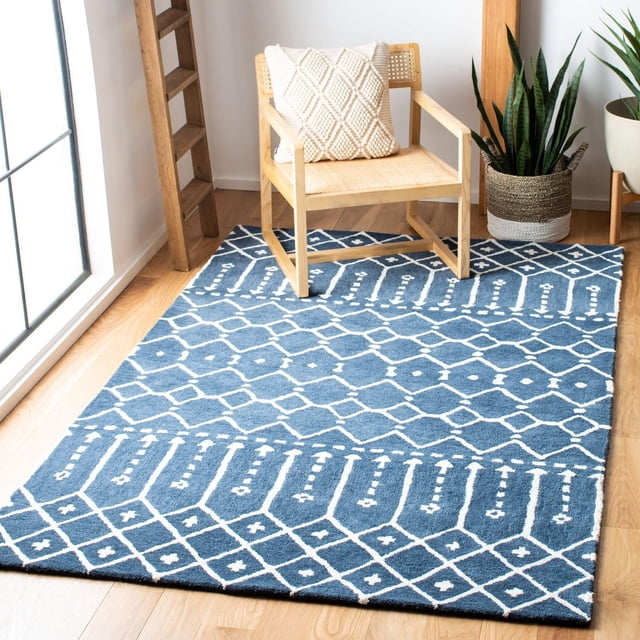 Safavieh Himalaya Darin Geometric Area Rug in blue with white geometric patterns, crafted from hand-loomed wool, displayed on light hardwood flooring under a wooden chair with a cream textured cushion, next to a woven basket planter with snake plants in a sunlit modern room, ideal for accentuating contemporary living spaces.