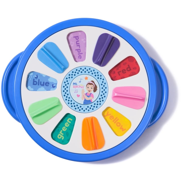 Ms. Rachel Spin Along Learning Wheel with 3 learning play modes, a round blue interactive toy featuring eight colorful tabs labeled with colors blue, purple, dark purple, red, pink, yellow, orange, and green, plus a central speaker with Ms. Rachel illustration, designed to support toddler learning of colors, sounds, and fine motor skills.