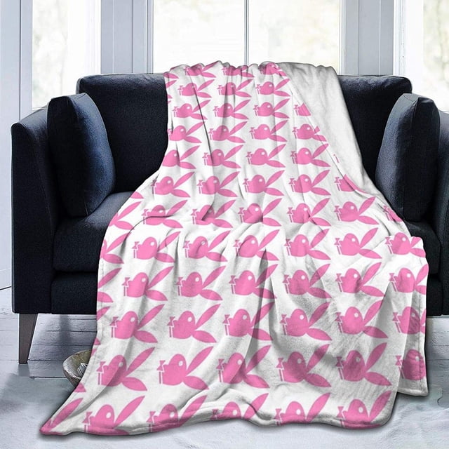 LAICAIW Pink Playboy Bunny Pattern Ultra-Soft Lightweight Blanket Flannel Throw Blanket 50"X40" draped over a dark armchair in a bright room. The blanket features a repeating pink bunny design on a white background, highlighting its single-sided printing and vibrant pattern. Made with 100% anti-pilling fabric, it is lightweight, cozy, and suitable for children, adults, and grandparents. Perfect for kids' bedding, adding warmth to a bed, or enhancing room decor with its elegant design.