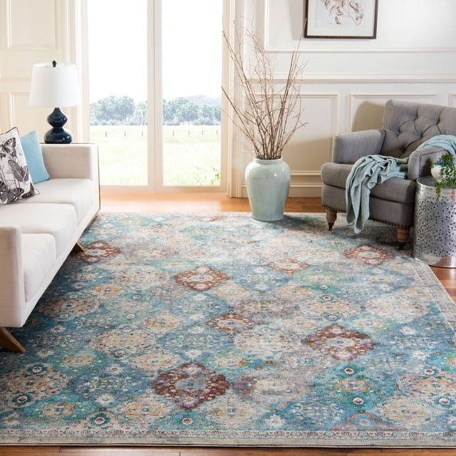 SAFAVIEH Luxor Harry Abstract Floral Area Rug featuring a blue and multicolored abstract floral pattern hand-knotted from satin-soft viscose yarns, displayed on hardwood flooring in a bright living room between a beige sofa and gray armchair, suitable for adding exotic elegance to home décor.