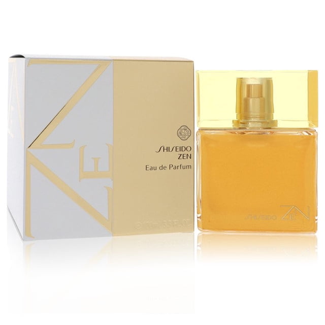 Zen by Shiseido Eau De Parfum Spray 3.4 oz, a fresh, floral woody fragrance with notes of grapefruit, pineapple, bergamot, peach, blue rose, freesia, and more. The image shows a rectangular glass bottle with golden liquid and a matching gold cap, placed next to its elegant white and gold packaging.