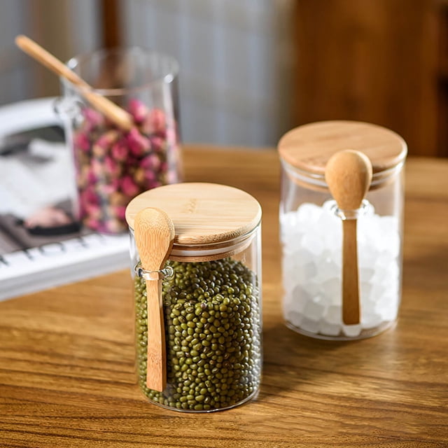 WIFKLSIIPG transparent glass food sealed lid spoon jar set, including four clear airtight jars with bamboo lids and attached wooden spoons. Each jar holds 17 oz and is perfect for kitchen organization, storing preserves, jams, tea, coffee, spices, or dry goods. The jars are displayed on a wooden surface, filled with items like green beans, sugar cubes, and dried flowers, ideal for meal prep containers.