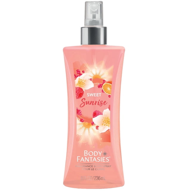 Body Fantasies Sweet Sunrise Body Spray 236ml in a translucent peach-pink bottle with a clear spray nozzle and silver collar, featuring a label with sunrise, white flowers, raspberries, and mandarin slices, highlighting its fruity floral scent with mandarin, honeysuckle, sandalwood, and vanilla notes.
