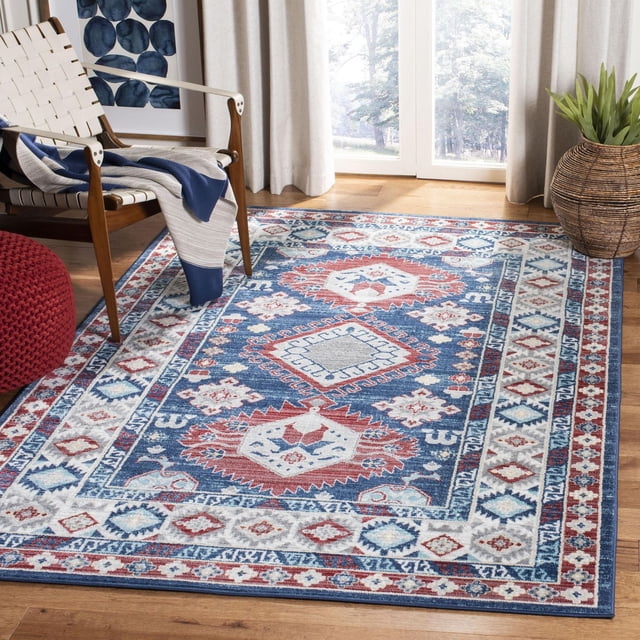 Safavieh Kazak Benson Tapis Géométrique Présentant de Vifs motifs Géométriques Bleus, Rouges et Blancs avec une Bordure Ornée, Fabriqué à Partir de Fils Synthétiques Durables à Poil Coupe Modérée, Placé sur un Plancher de Bois Franc dans une Pièce Éclatante avec un Fauteuil Tissé, un pouf Tricoté Rouge et un Panier Tissé à planter Près de Grandes Fenêtres avec des Rideaux Légers.