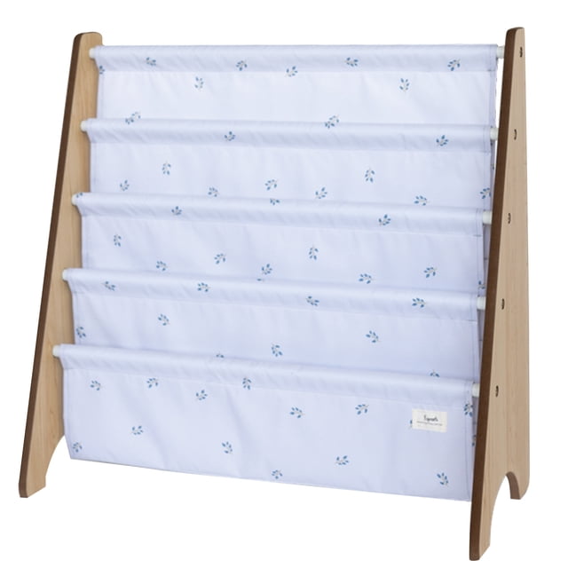 3 Sprouts - mist blueberry recycled fabric book rack featuring a wooden frame with four fabric pockets made of 100% recycled polyester. The fabric is light blue with a subtle blueberry print. Designed for kids, it is the perfect height for easy access to books and encourages reading by displaying books face forward. Dimensions are 24 inches in height, 24.5 inches in width, and 10 inches in depth. Easy to assemble with included instructions.