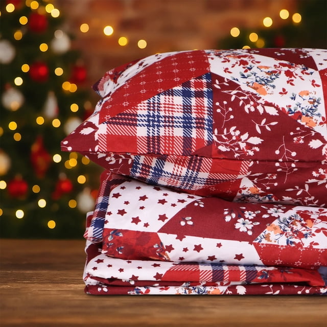 Hitime Ensemble de Draps de Noël 3 Pcs Format Jumeau Présentant un Motif Classique Rouge et Blanc à Empiècements avec des Motifs à Carreaux, Floraux et d'Étoiles. Fabriqué en polyester Ultra Doux et Respirant, Cette Literie Rafraîchissante pour Toutes les Saisons Est Résistante aux Plis et à la Décoloration. les Draps Sont Exposés Pliés sur une surface en Bois avec un Sapin de Noël Festif et des Lumières Chaudes en Arrière-Plan.